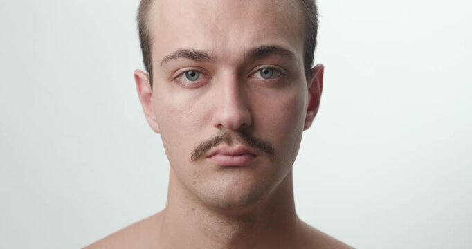 Studio Close-Up Portrait of Young Caucasian Man with Mustache Looking at Camera