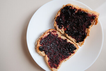 Golden toasted bread slices spread with rich dark berry jam © renipurnama