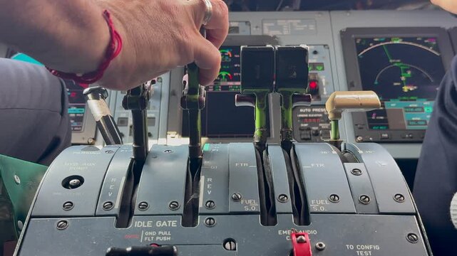 Closeup view of the hand of a caucasian pilot adjusting the thrust levers for takeff in a modern turboprop airplane cockpit. low angle 4K shot.