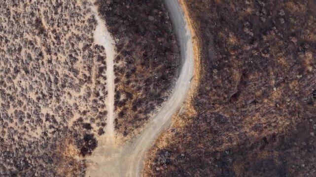 Aerial view looking down on a lone hiker traversing the hot rugged mountain trail in Southern California