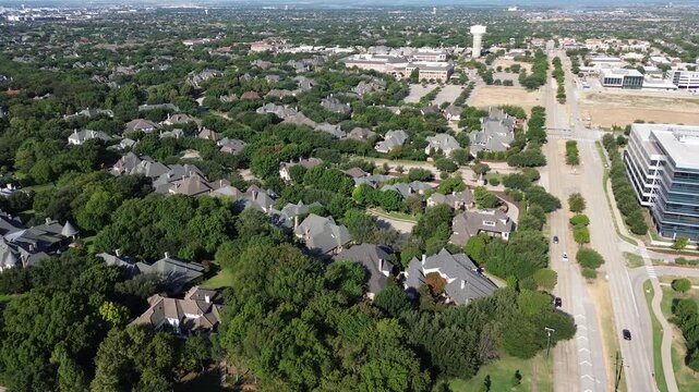 Sleek glass high rises flank Starwood neighborhood along Warren Parkway. Distinctive rooflines merge into mature suburban tree canopies, illustrating upscale regional growth across Frisco, Texas