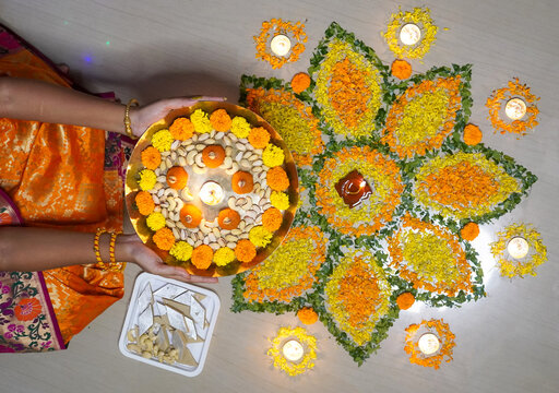 Indian girl holding hand flower plate for Diwali celebration by looking at camera at home concept of - Indian traditional, ceremony and festival preparation.