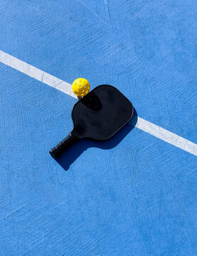 Pickleball paddle and ball on blue court line