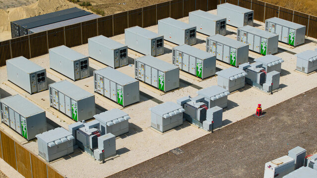 Aerial view of Bicker Fenn Battery Energy Storage Systems with rows of grey storage containers and green energy logos on a gravel site in Boston, England, United Kingdom.