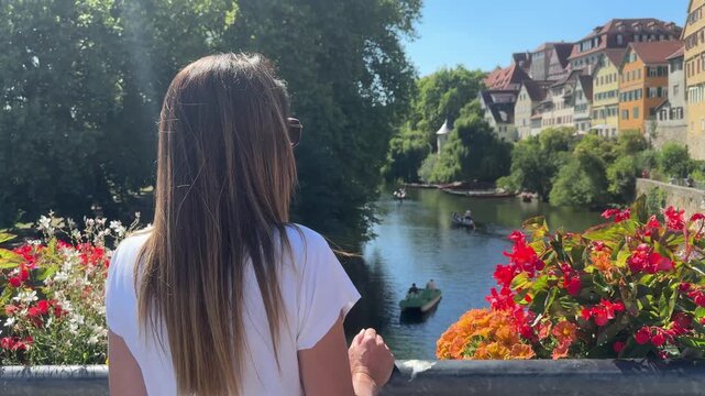 woman standing on a bridge admiring the picturesque view of the Neckar river and the colorful old town of Tubingen, Germany