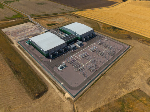 Aerial view of Viking Link HVDC Converter Station with large industrial buildings and electrical infrastructure surrounded by agricultural fields in Donington, England, United Kingdom.