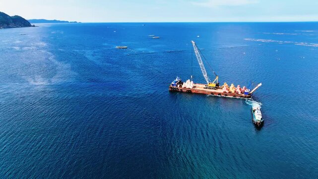  Aerial 4K view of a tugboat towing a barge near Jangho Port in Samcheok, South Korea