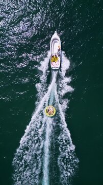 Aerial View of Speedboat Towing Inflatable Tube on Deep Blue Sea