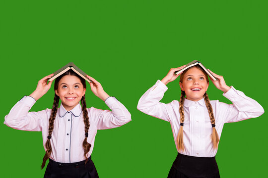 Portrait of two person nice attractive lovely charming cute cheerful cheery playful foolish pre-teen girls holding book like roof on head isolated over bright vivid shine orange background
