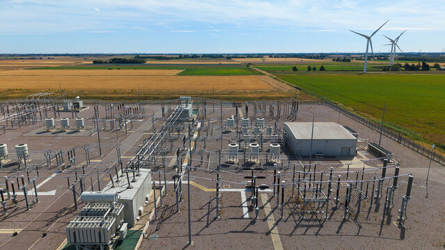 Aerial view of the Triton Knoll offshore windfarm 400220kV substation with electrical infrastructure and wind turbines in the background in Boston, England, United Kingdom.