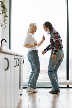 An elderly couple joyfully dances together in their home, celebrating their enduring love and connection