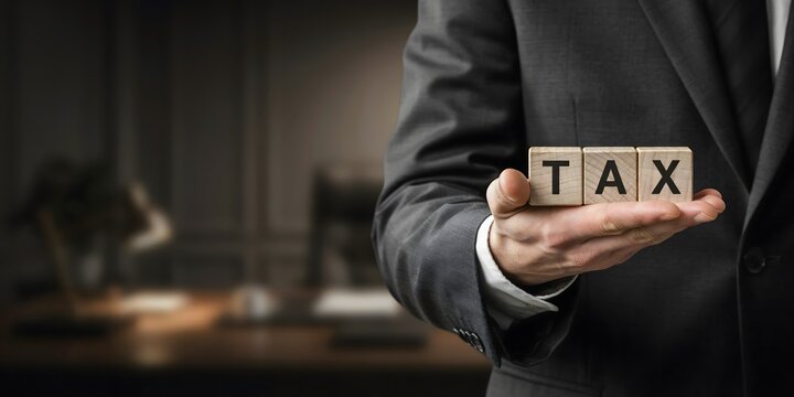 Tax Concept With Businessman Holding Wooden Letter Blocks Representing Income Tax Finance Accounting Payment And Government Revenue