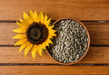 Naklejka premium Healthy nutrition and organic food, sunflower seeds in a wooden bowl with a fresh yellow flower on a rustic table for natural diet and vegan snacks