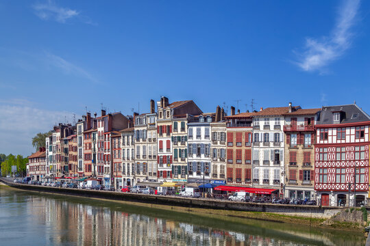 Historical houses line the scenic Nive river embankment in Bayonne, France. Bright daylight showcases traditional style, no people