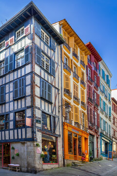 Historical Basque houses with bright colorful window shutters on a street in Bayonne, France. Sunny daylight view, no people