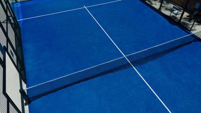 Aerial view of a vibrant padel court with dynamic shadows on a sunny afternoon