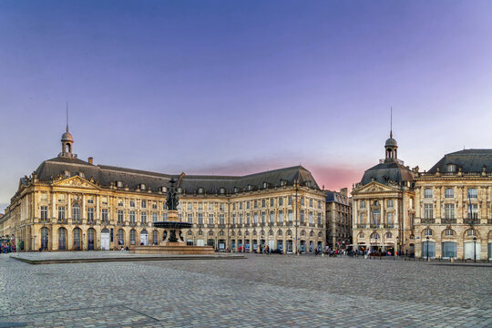 Asymmetric view of Place de la Bourse palace facade under a colorful sunset sky in Bordeaux, France. Elegant classical style