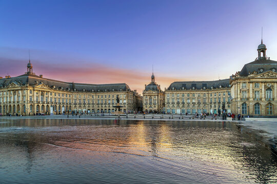 Panoramic view of Place de la Bourse with the central fountain under a sunset sky in Bordeaux, France. Elegant historic palace