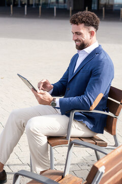 Businessman using digital tablet while sitting outside modern office building