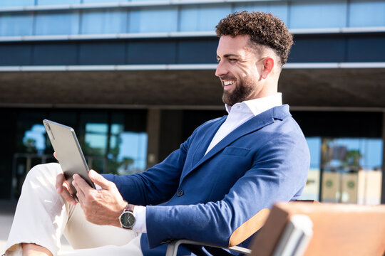 Businessman using digital tablet while sitting outside modern office building