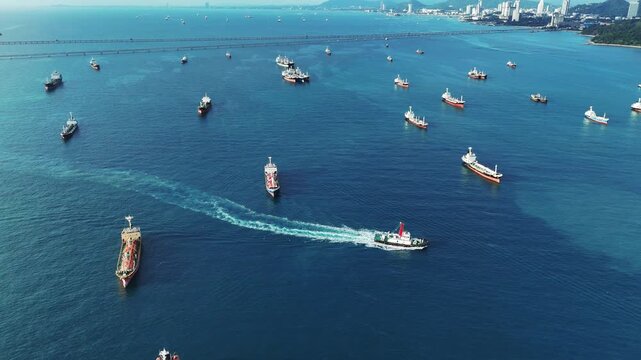 Fleet of oil tanker ships and commercial cargo vessels anchored in the deep blue sea near a long bridge. Global maritime logistics, international shipping trade, and energy transport.