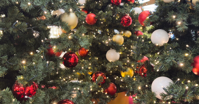 Close-up of golden and red Christmas ornaments on festive tree with holiday lights