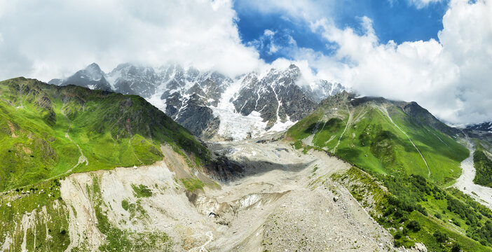 Svaneti Shkhara glacier. Summer with clouds drift across rugged peaks, moraine rocks foreground. Travel Svaneti explore Georgia