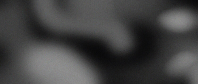 Abstract dark grey grainy background with soft blurred light spots