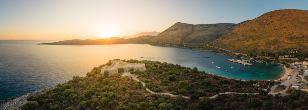 Aerial view of the historic Ali Pasha Castle on a peninsula in Porto Palermo bay at sunset, with calm sea, rocky hills, and small boats in the harbor, Porto Palermo, Qarku i Vlores, Albania.