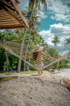 Woman tourist stay under shadow of the coconut trees at the edge of the sea beach, cheerfully traveling life in summer of the island