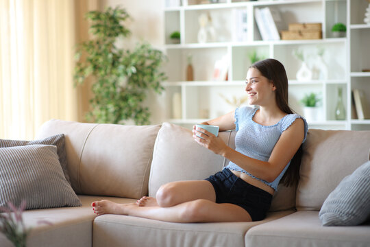 Happy teenage girl holding coffee cup looking away