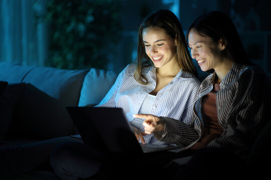 Happy women watching media on laptop in the night