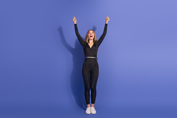 Young woman in striped jumpsuit celebrates success against blue background
