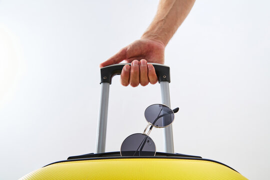 Man Hand Holding Yellow Suitcase Handle with Sunglasses