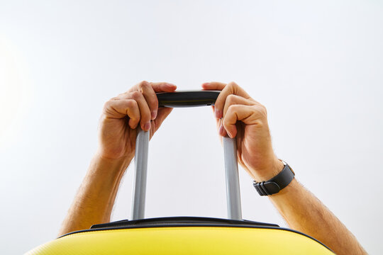 Low angle view of hands holding telescopic handle of yellow luggage suitcase