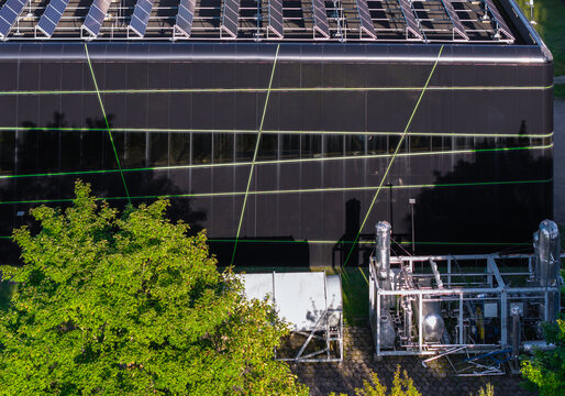 Aerial view of the Renewable Energy Technology Laboratory with a dark facade, green geometric lines, rooftop solar panels, and industrial equipment in Gdansk, Pomeranian Voivodeship, Poland.