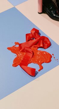 Red ribbon streamer flowing like liquid on a blue and white diner floor, featuring a ribbed texture and glossy finish with copy space for a campaign