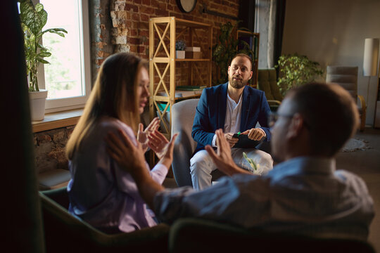 Couple having serious conversation with male family psychologist in private office. Concept of emotional honesty, difficult conversation, relationship help.