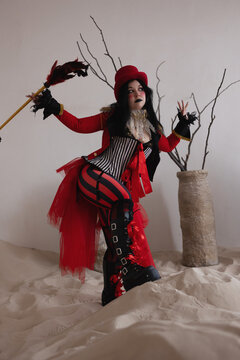Ringmaster in red costume raising arms in triumphant gesture beside bare branches in vase
