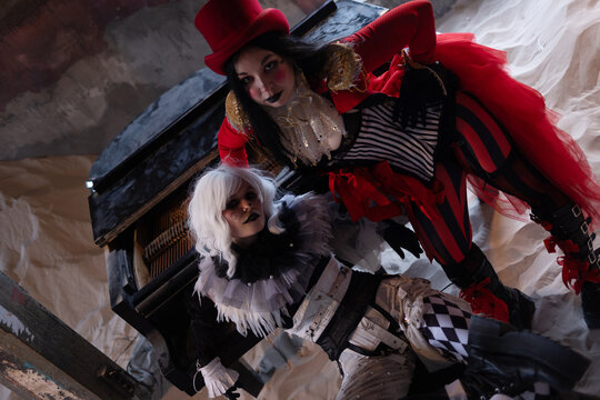 Two performers by an old piano in dramatic interaction inside sand filled ruin