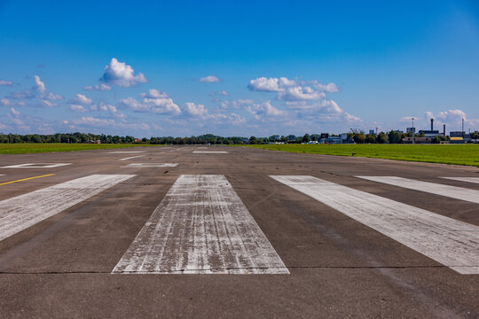 Aerial view of S. Darius and S. Girenas Aerodrome runway with white markings, surrounded by green fields under a clear blue sky in Kaunas, Kaunas County, Lithuania.