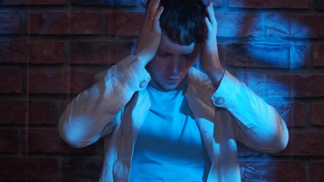 Tired unhappy young adult man with headache migraine at home.