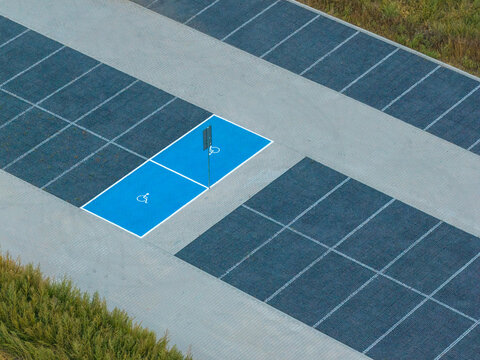 Aerial view of two blue painted accessible parking spaces with wheelchair symbols in a paved parking lot in Poznan, Greater Poland Voivod, Poland.