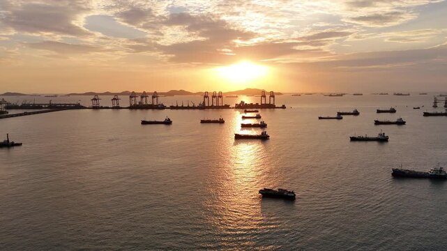 Silhouettes of gantry cranes and cargo ships at a bustling seaport during a dramatic golden sunset. Global maritime logistics, international trade, and industrial shipping transport concept.