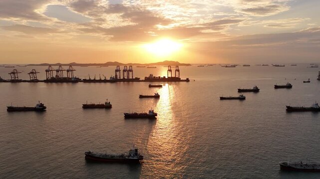 Silhouettes of gantry cranes and cargo ships at a bustling seaport during a dramatic golden sunset. Global maritime logistics, international trade, and industrial shipping transport concept.