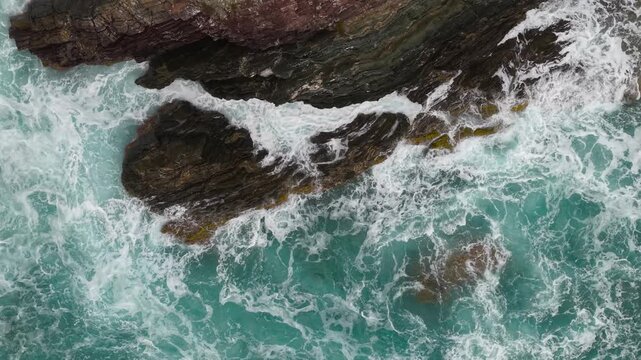 Rough Waves Break Around The Pan di Zucchero Sea Stack And Limestone Cliffs Along The Coast Of Masua In Sardinia, Italy. Aerial top-down shot
