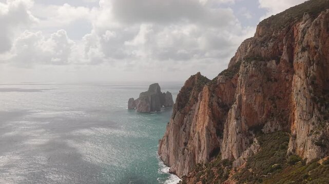 Pale Grey Limestone Cliffs Overlook The Pan di Zucchero Sea Stack Along The Coast Of Masua, Sardinia, Italy. Aerial Shot