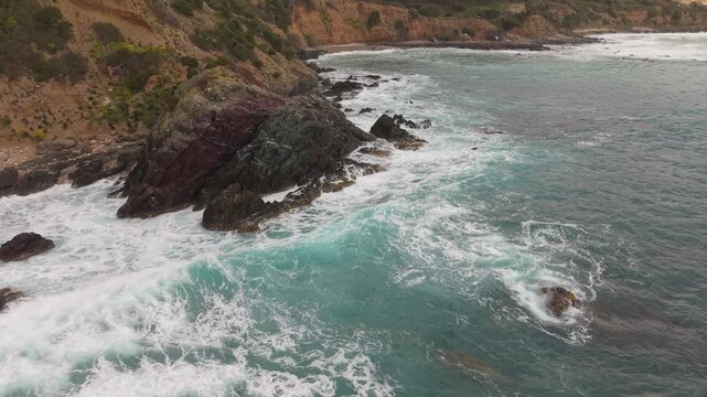 Breaking Waves Crashing Along The Rocky Coast Near Pan di Zucchero And Porto Flavia In Masua, Sardinia, Italy. Aerial Drone Shot