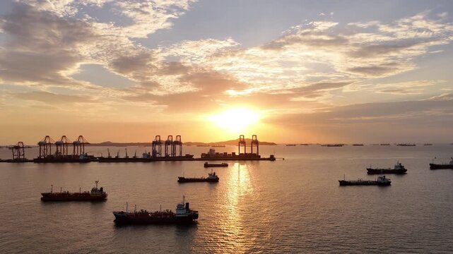 Silhouettes of gantry cranes and cargo ships at a bustling seaport during a dramatic golden sunset. Global maritime logistics, international trade, and industrial shipping transport concept.