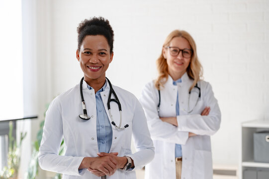 Portrait of two diverse female physicians standing confidently together, representing women, diversity and inclusion in modern healthcare